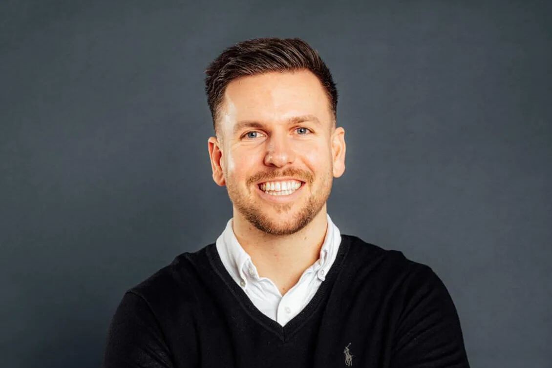 Geschäftsführer Sam Finnern steht frontal zur Kamera und hat die Arme verschränkt.